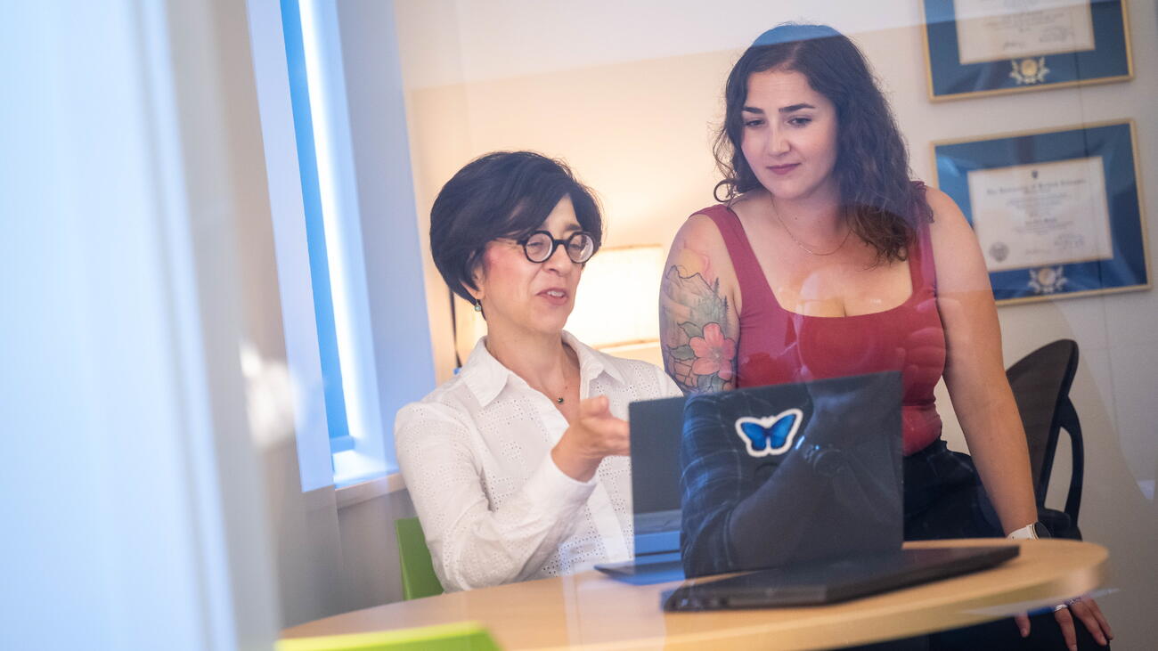 Two women talk in front of laptop in office