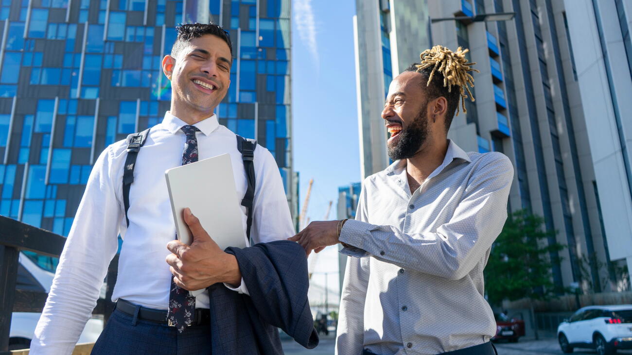 Two businessmen laugh and walk in business district