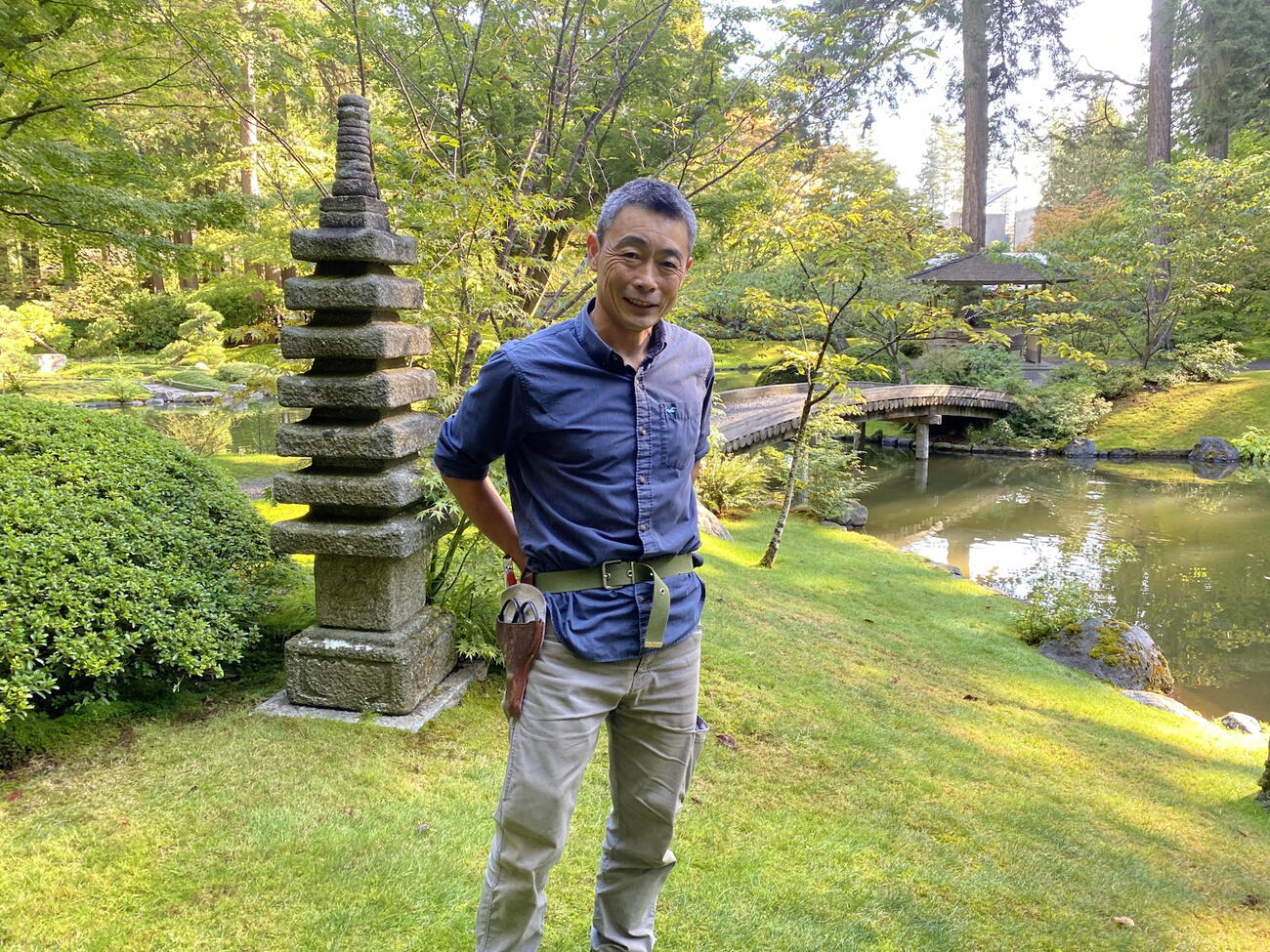 Asian man stands in garden in front of stone ornament