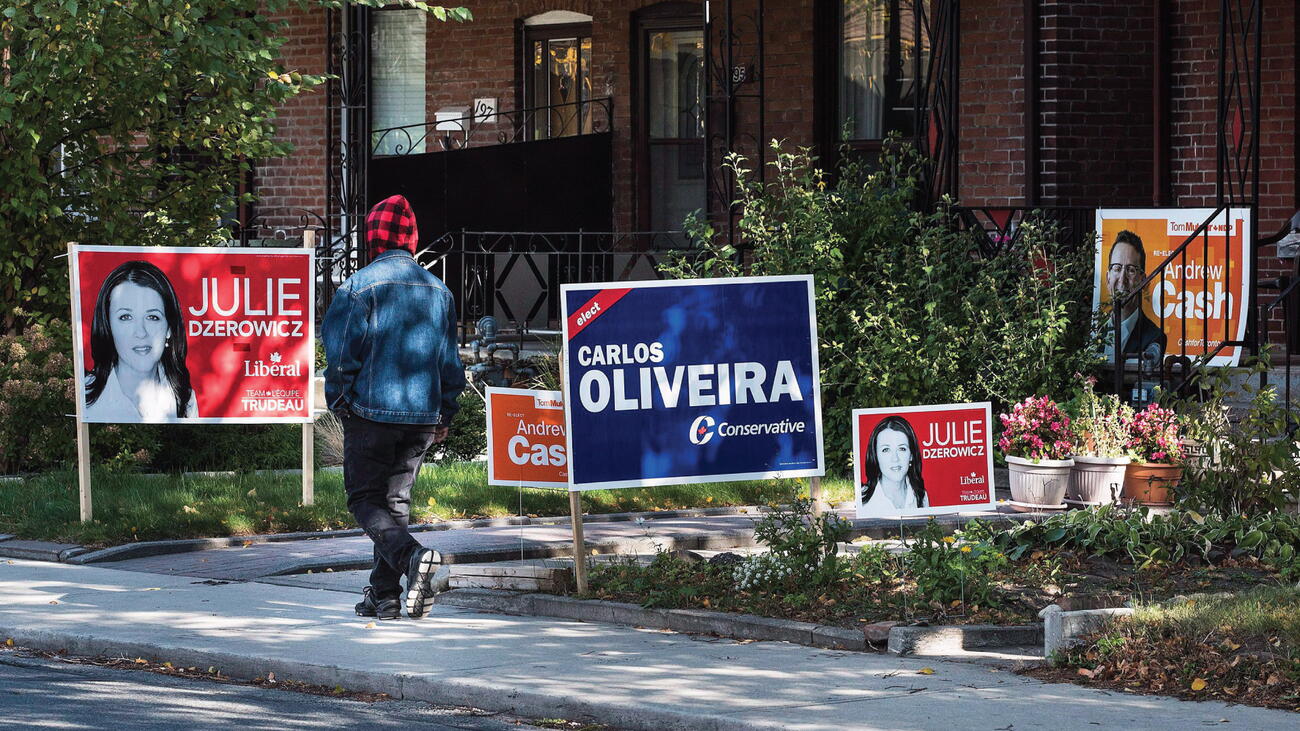 Campaign signs on a lawn as a person walks by