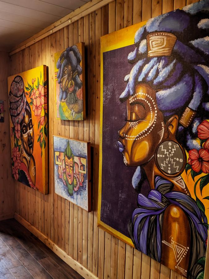 An angled shot of four pieces of colourful artwork on the wall, by Kenyan artists