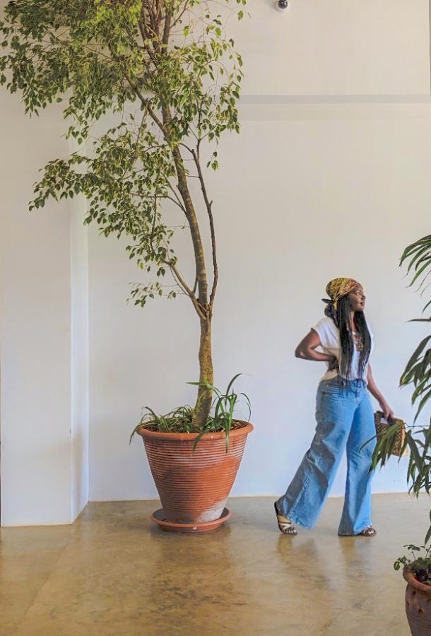 Mwango standing next to a tall indoor plant inside a gallery in Nairobi