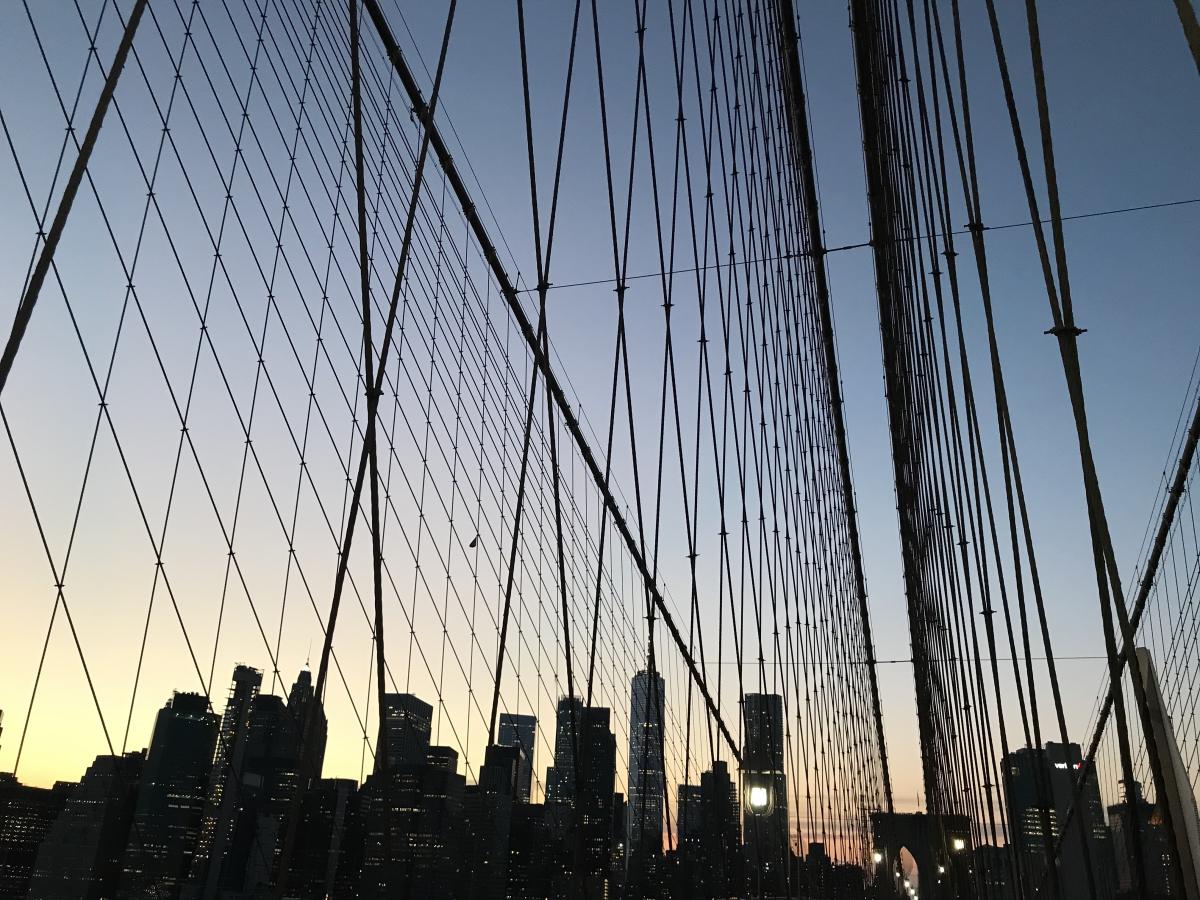 Silhouette of the Brooklyn Bridge and buildings behind it at twilight