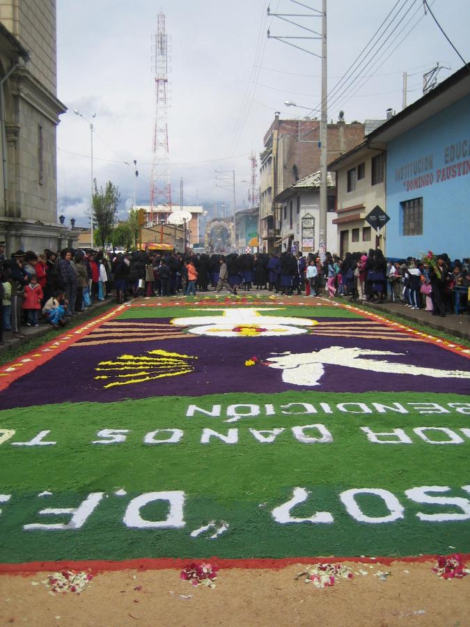 A view of the Mes Morado (Purple Month) procession coming toward the camera to cross the colourful carpet of dyed sawdust prepared for its arrival
