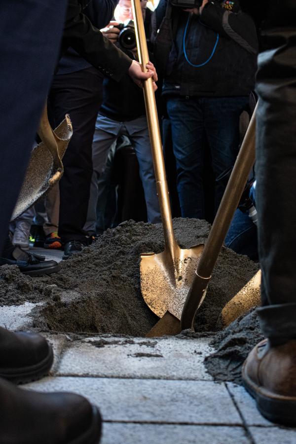People with shovels digging hole in ground