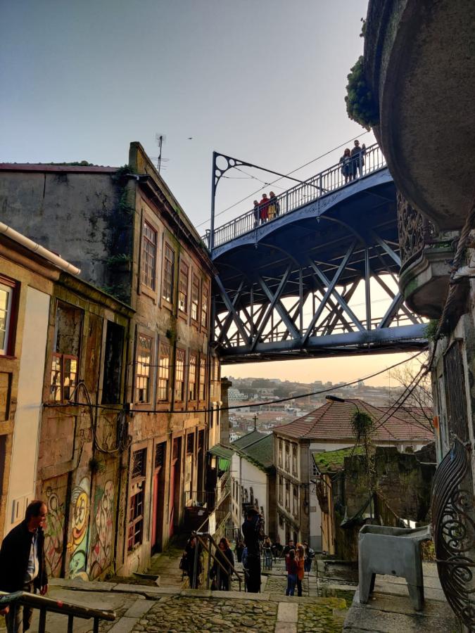 A street in Porto with a view of the Dom Luis Bridge overhead.