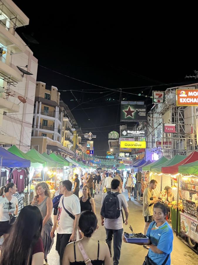 Pedestrians walking along a street full of booths/stalls at nighttime