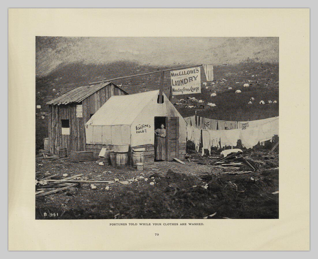 A laundress looks out from the doorway of her tent 