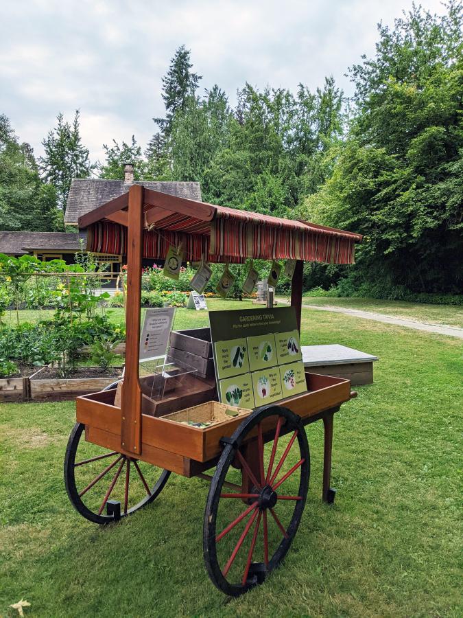 An outdoor cart displaying objects and an interpretive panel at the Burnaby Village Museum
