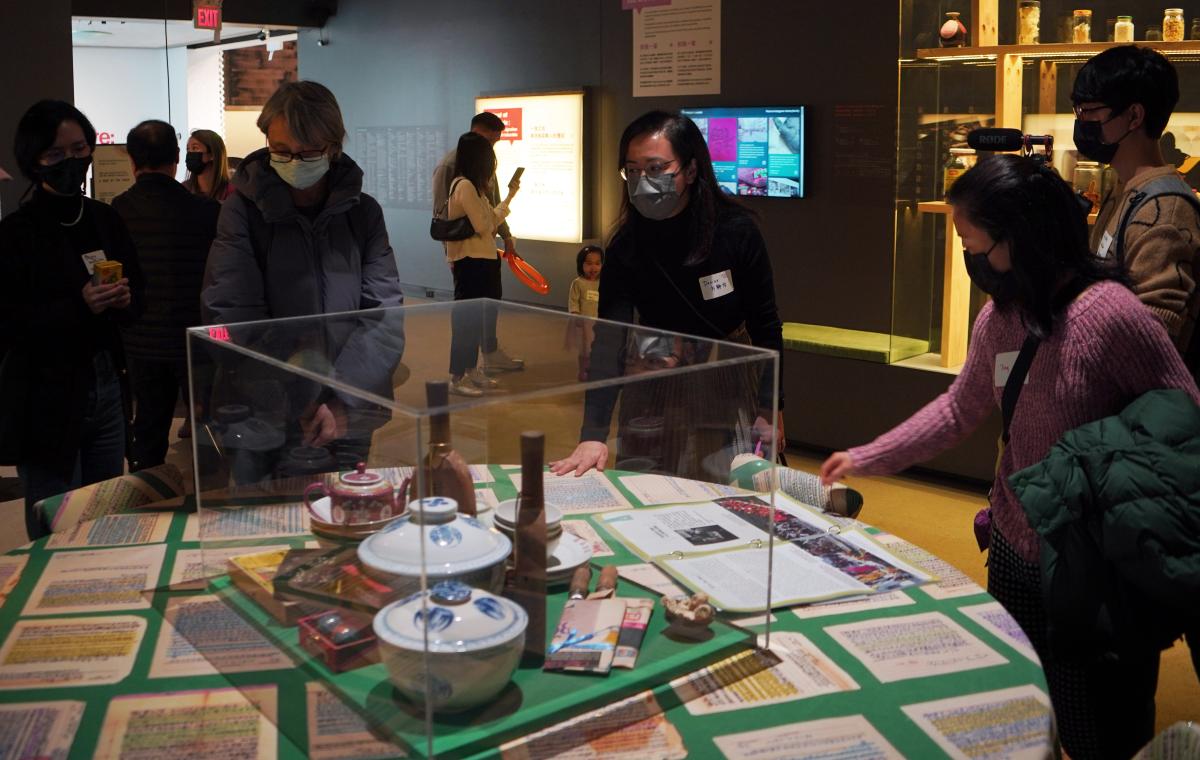 Visitors looking at objects displayed on a table at A Seat at the Table exhibition