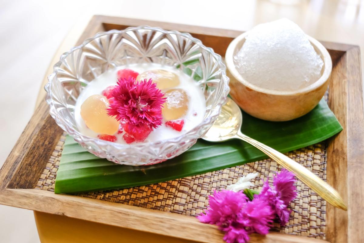 A glass bowl containing a Thai dessert (Tub Tim Krob), on a wooden tray