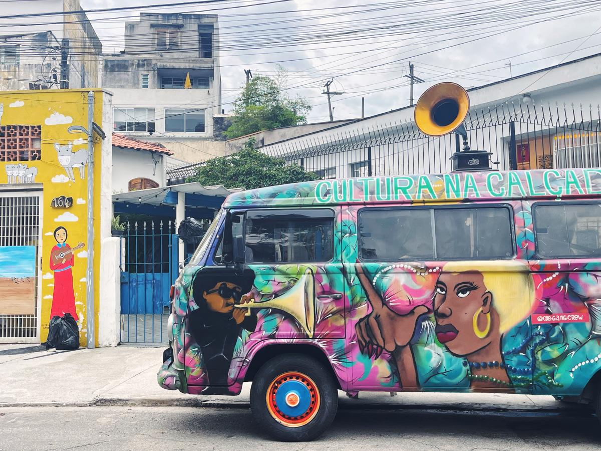 A van covered in a colourful mural parked on a street in the neighbourhood of Vila Madalena