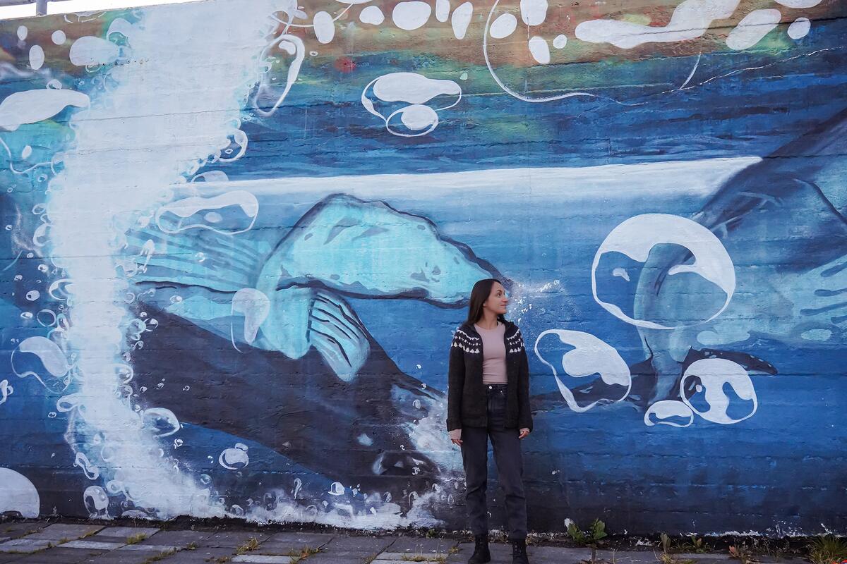 Charla Basran in front of a whale mural in Húsavík