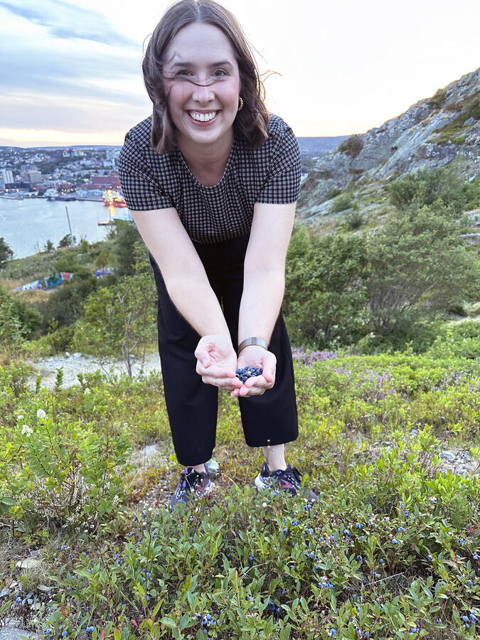 Dr. Amy Dawson on Signal Hill holding a handful of wild blueberries