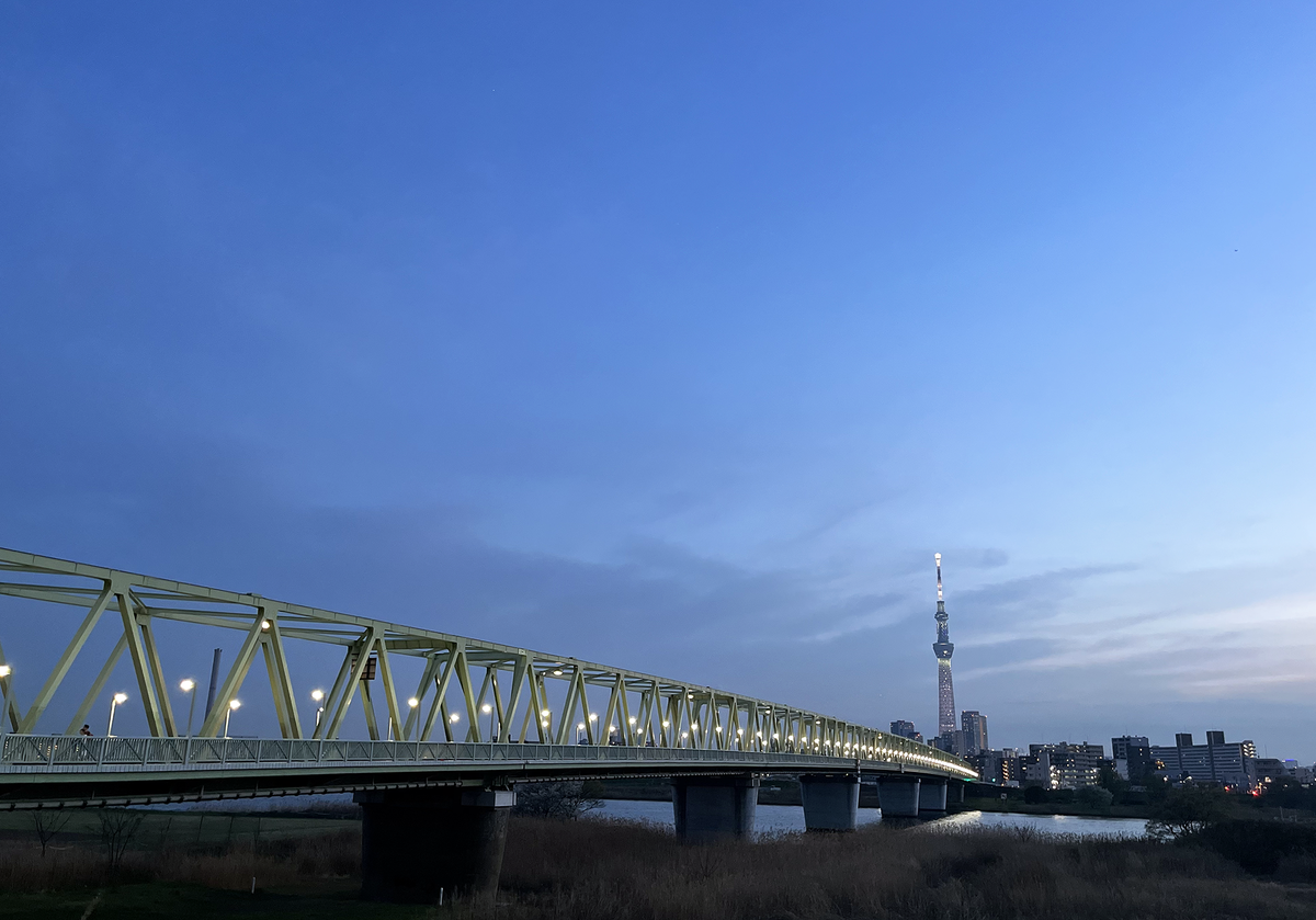 A view at dusk of Tokyo Skytree, the tallest freestanding tower in the world, with a bridge in the foreground