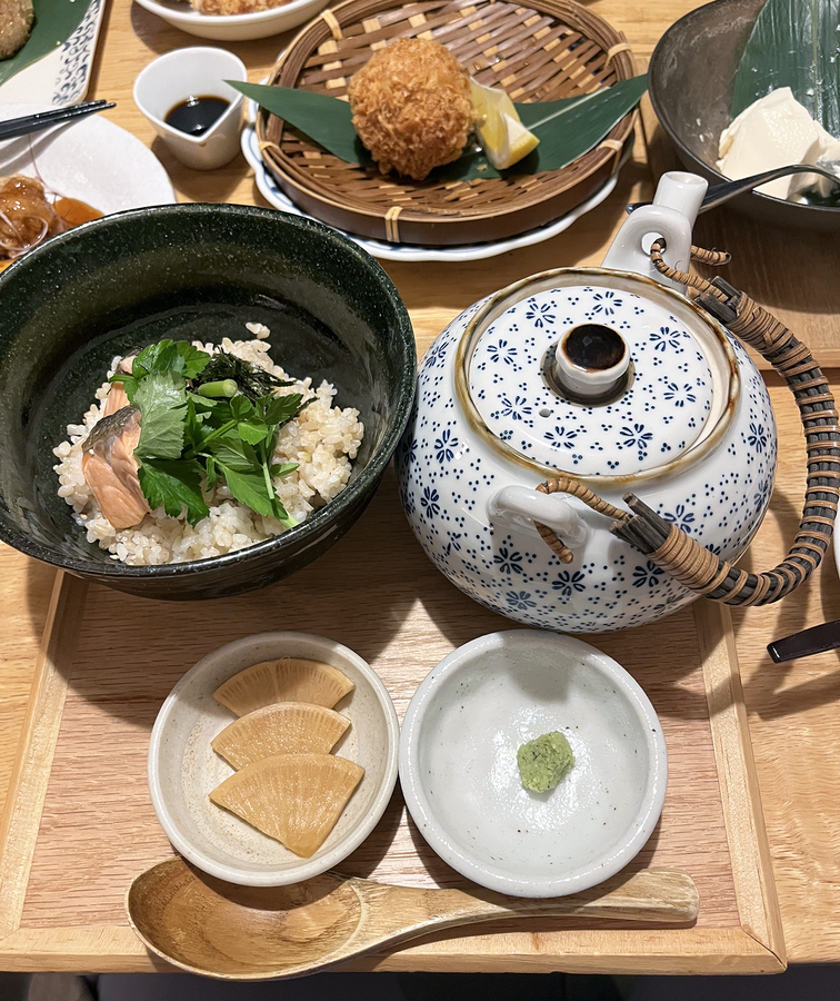 A bowl of ochazuke, a tea pot, and various small dishes laid out on a table