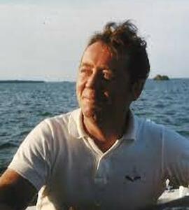 A photo of James Richard Gorwill wearing a white collared shirt against an ocean backdrop.