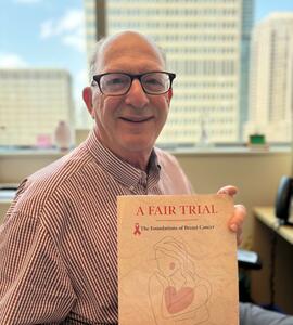 A photo of Steven Narod holding up a copy of A Fair Trial