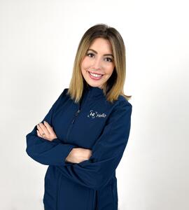 A photo of Kortnee Paiha wearing a blue jacket with the words 'Hi Hello' on it, standing against a white background