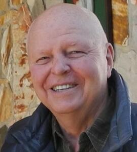 Headshot of Ray Johnson wearing a puffer jacket and black collared shirt.