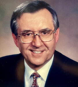 A photo of Dr. Kurt N. Gottschling in a black and white suit and glasses