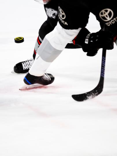 Legs of hockey players and referee on ice as puck drops