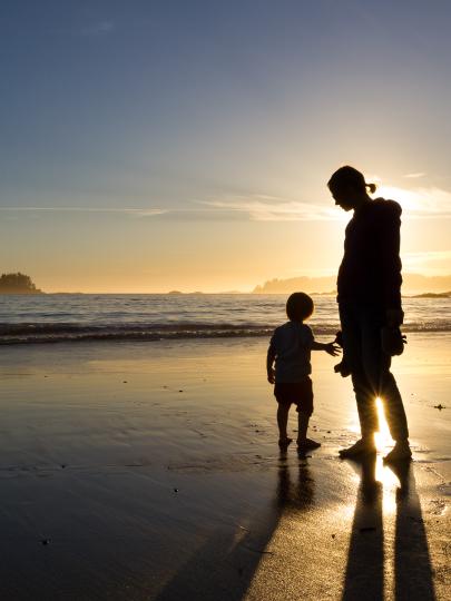 Silhouette of a mother and child on a beach at sunset