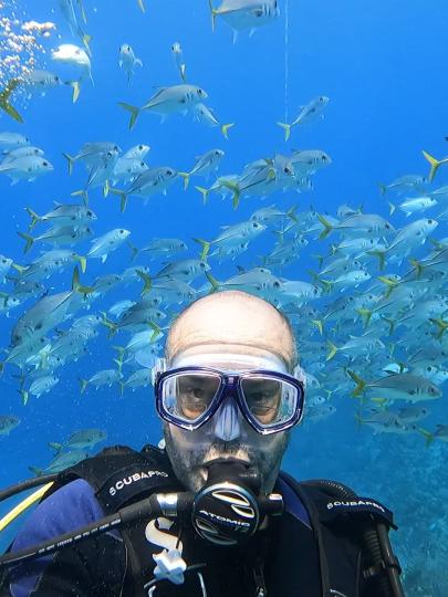 Headshot of Brian Patterson in scuba diving gear with fish in the background
