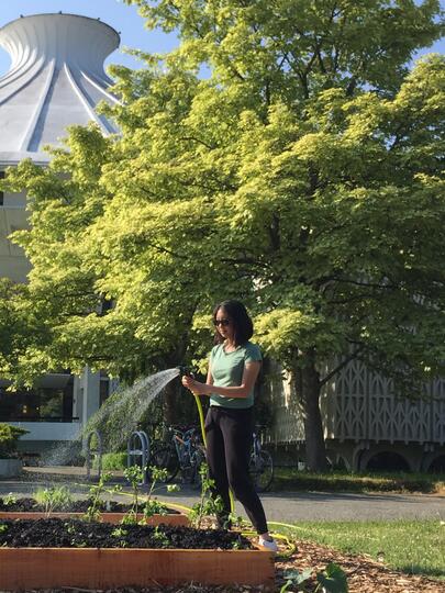 A UBC student waters a garden outside the Museum of Vancouver on a sunny day