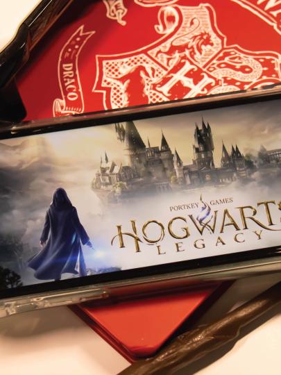 Hogwarts Legacy game displayed on smartphone beside game controller
