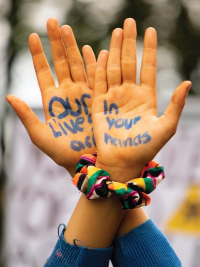 Words written on two hands held in the air at protest
