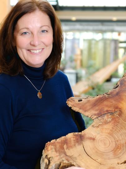Headshot of Dr. Lori Daniels holding a cross-section of a tree trunk