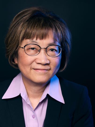 A headshot of Dr. Teresa Tsang with black glasses, short brown hair, and a purple collared shirt.