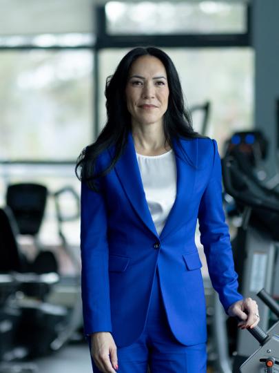 Woman in suit stands in gym with exercise machines