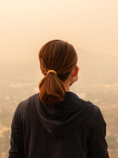 Woman sitting facing city shrouded in haze