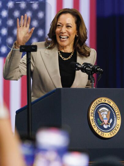 Kamala Harris waves to crowd from podium in front of US flag