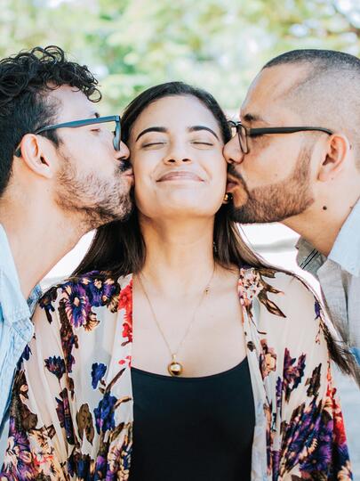 A woman being kissed on either cheek by two people