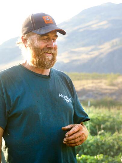 Yuri Zebroff standing on his farm property with mountains in the background