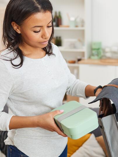 Mother putting lunchbox into boy's backpack