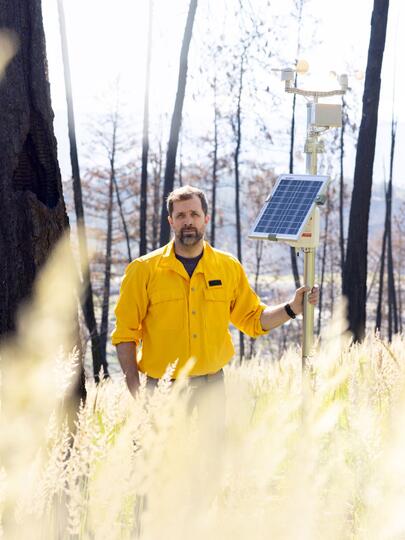 Man standing in field holding pole with devices attached