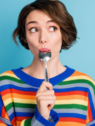 Student holding a spoon in her mouth with a surprised expression