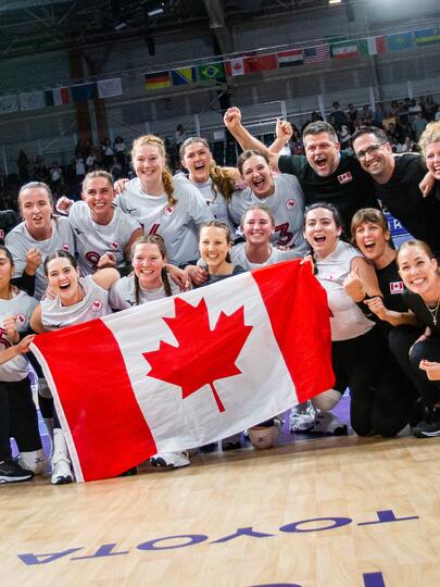 Athletic team cheering and holding Canadian flag in a gym