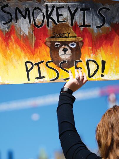 Woman holds wildfire protest sign at Canada's Parliament Hill