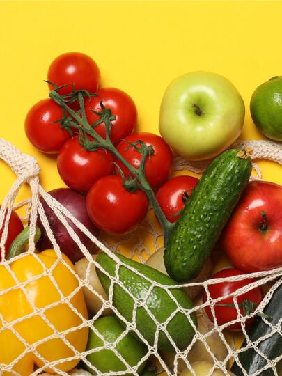 Vegetables in a mesh grocery bag against a yellow background