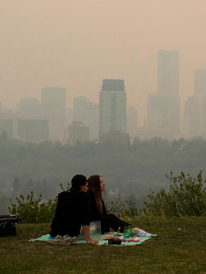 Couple having a picnic with smog-clouded city skyline in background