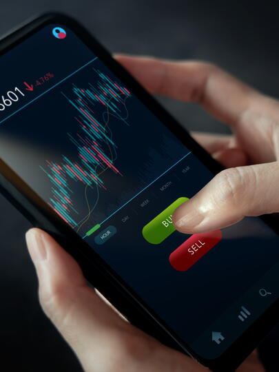Woman's hands on smartphone displaying stock market graphics