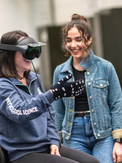 Woman wears VR headset and gloves as another woman watches 