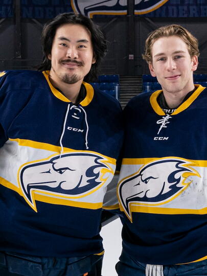 Two hockey players stand side by side in ice rink