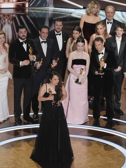 Samantha Quan giving her acceptance speech with the cast and team of her Oscar-winning film behind her