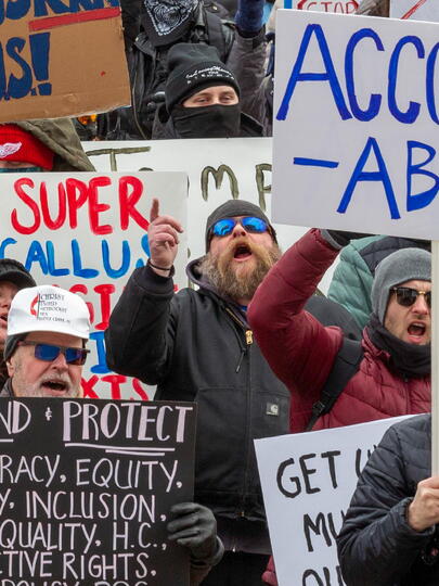 Photo of people protesting and holding up signs. One sign says: "Accountability."